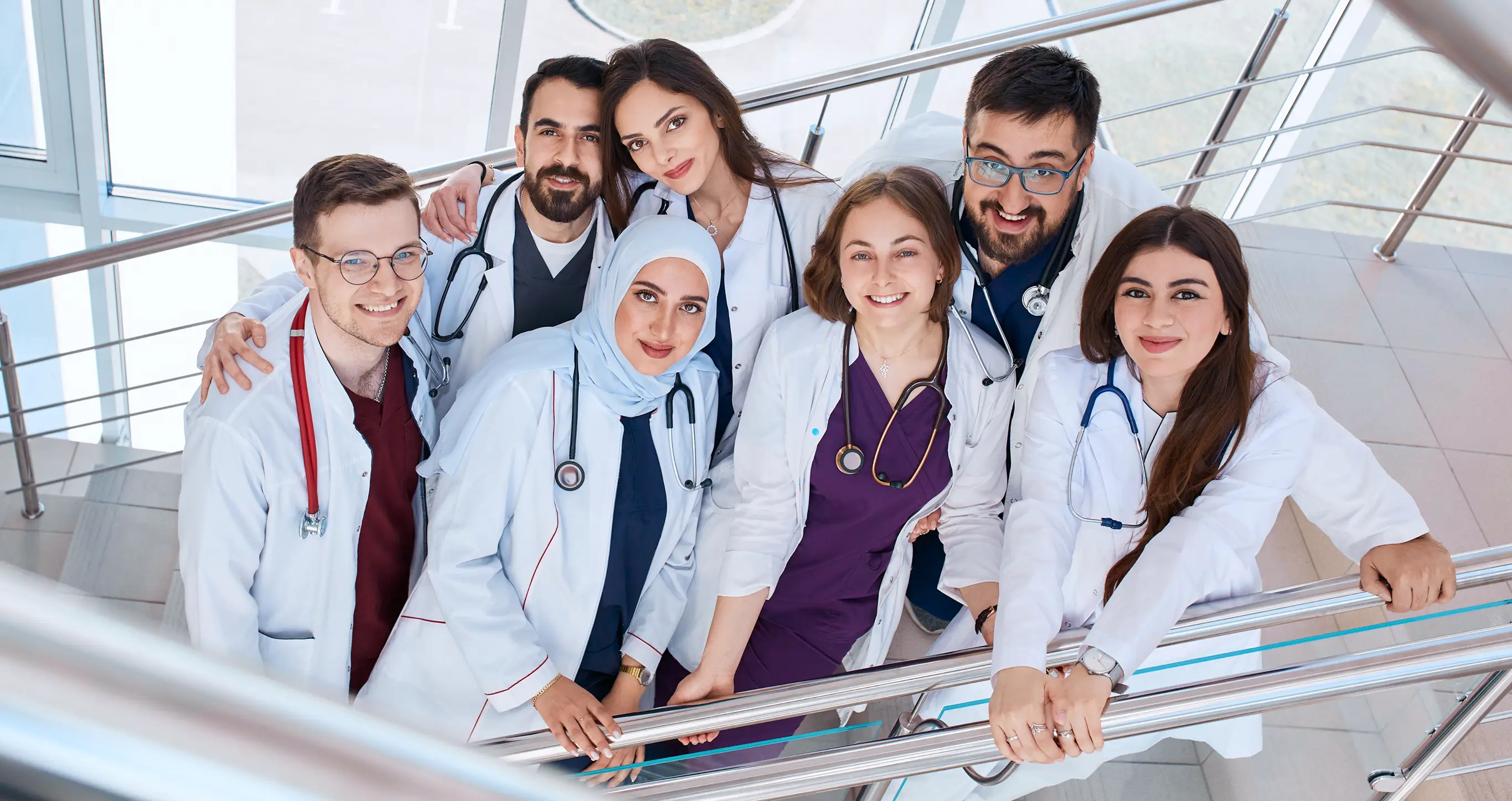 Smiling medical students in white coats in a hospital corridor